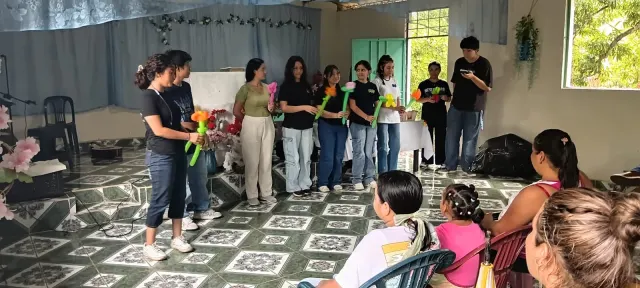 Jóvenes representando una escena teatral frente a personas sentadas en el templo.