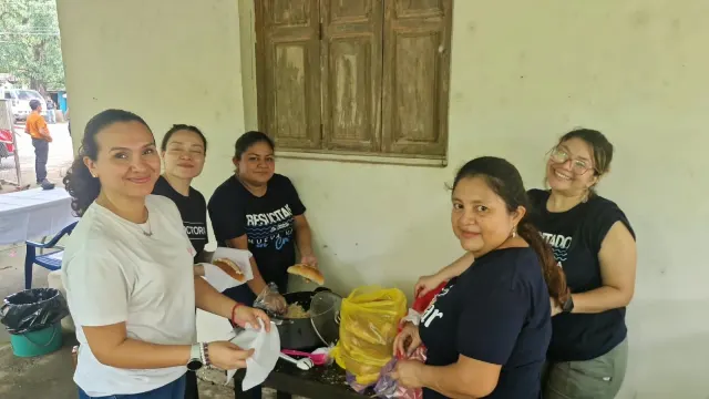 Cinco colaboradoras organizando panes e ingredientes sobre una mesa.