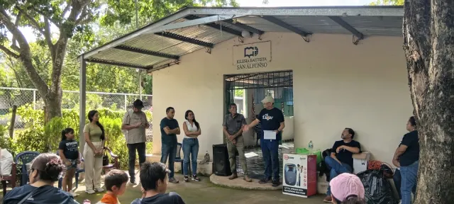 Participantes escuchando a coordinador que habla frente a la entrada del templo.