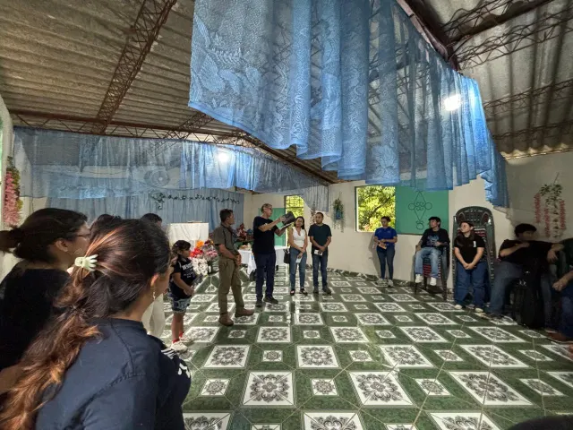 Grupo de colaboradores reunidos en el templo mientras una persona dirige unas palabras.